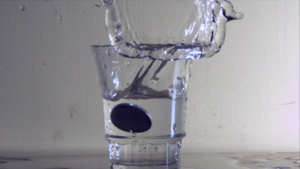Slow motion image of coin toss in water glass filmed with Fastec high speed camera